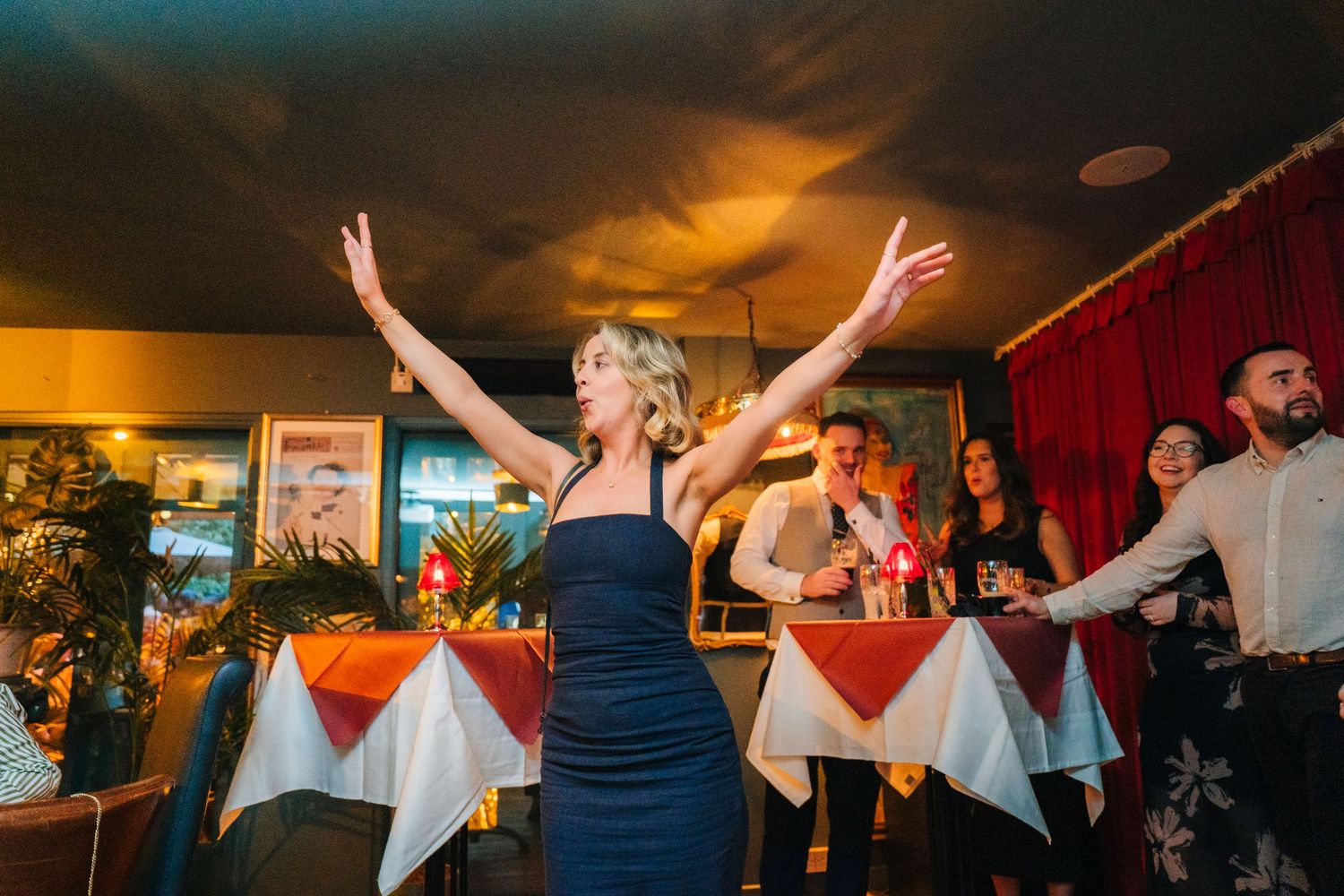 A joyful celebration scene in a restaurant with people dancing and raising their arms under warm lighting. Marco Pierre Dublin Wedding Photo