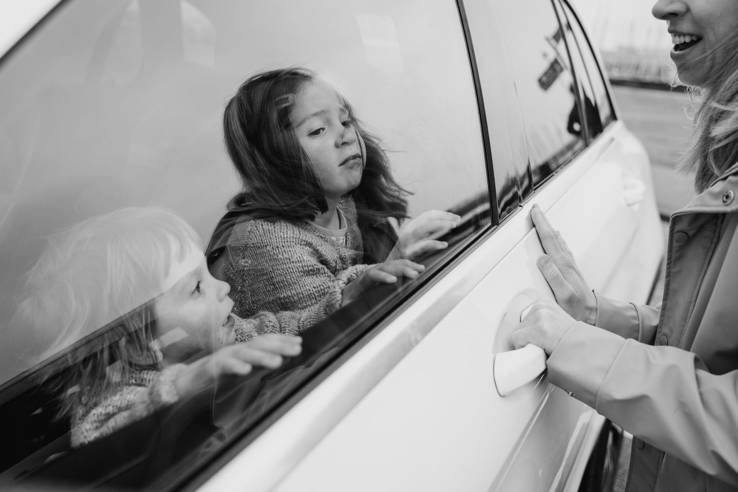 Black and white photo of children looking through a car window with reflections. PHOTOGRAPHER Dublin