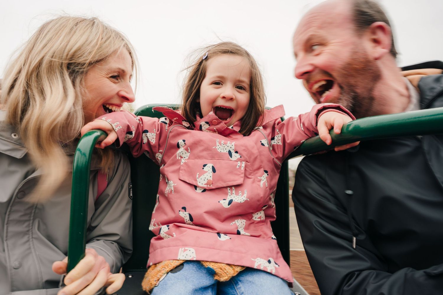 A joyful candid family moment showing laughter and interaction while wearing pink and dark colored clothing. PHOTOGRAPHER Dublin