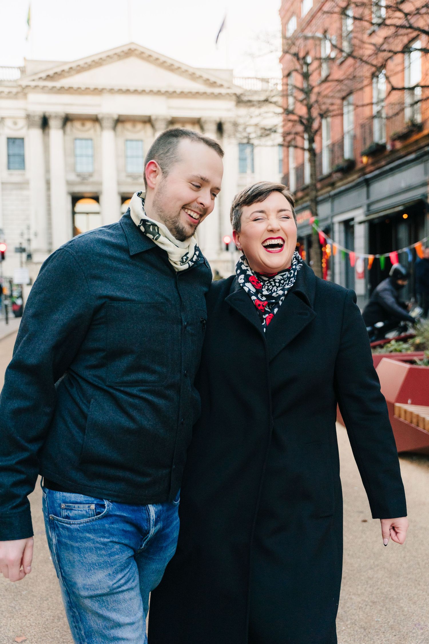 Two people sharing a joyful moment together while walking outdoors in winter coats.