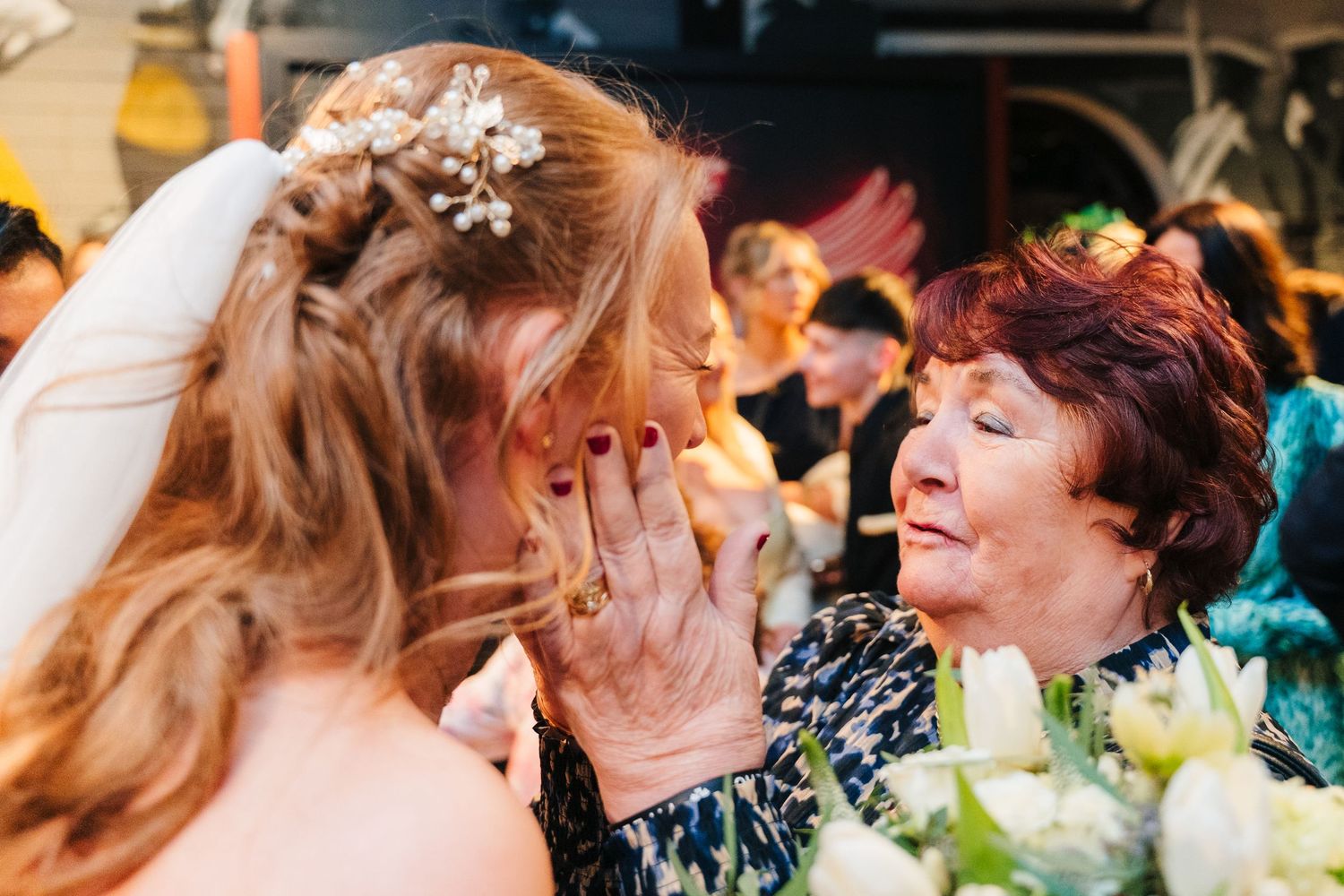 An emotional moment shared between a bride in white and an older woman during a wedding celebration. Dublin wedding photogrAPher