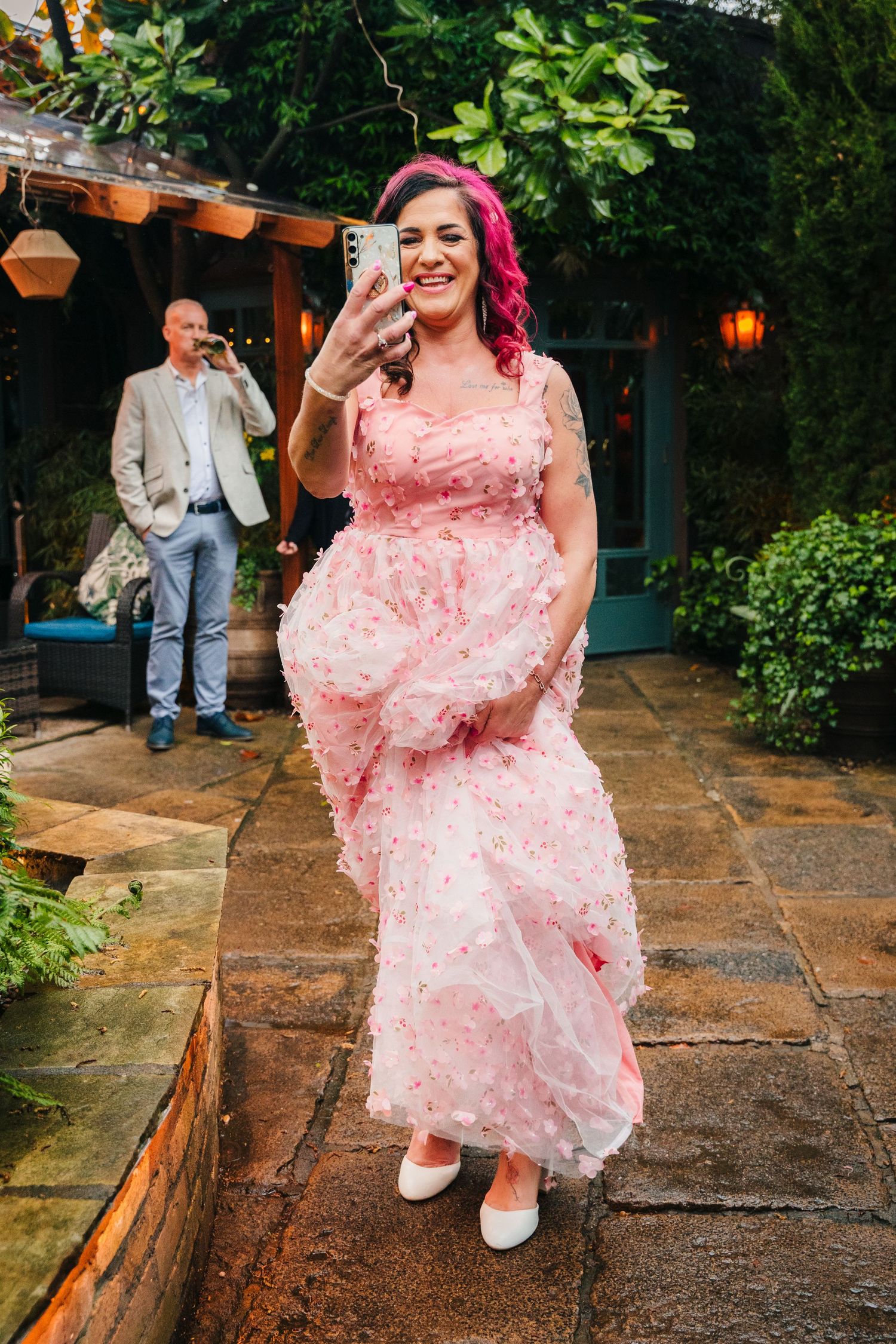 Person in a flowing pink gown taking a selfie in an outdoor garden setting. Marco Pierre Dublin Wedding Photographer