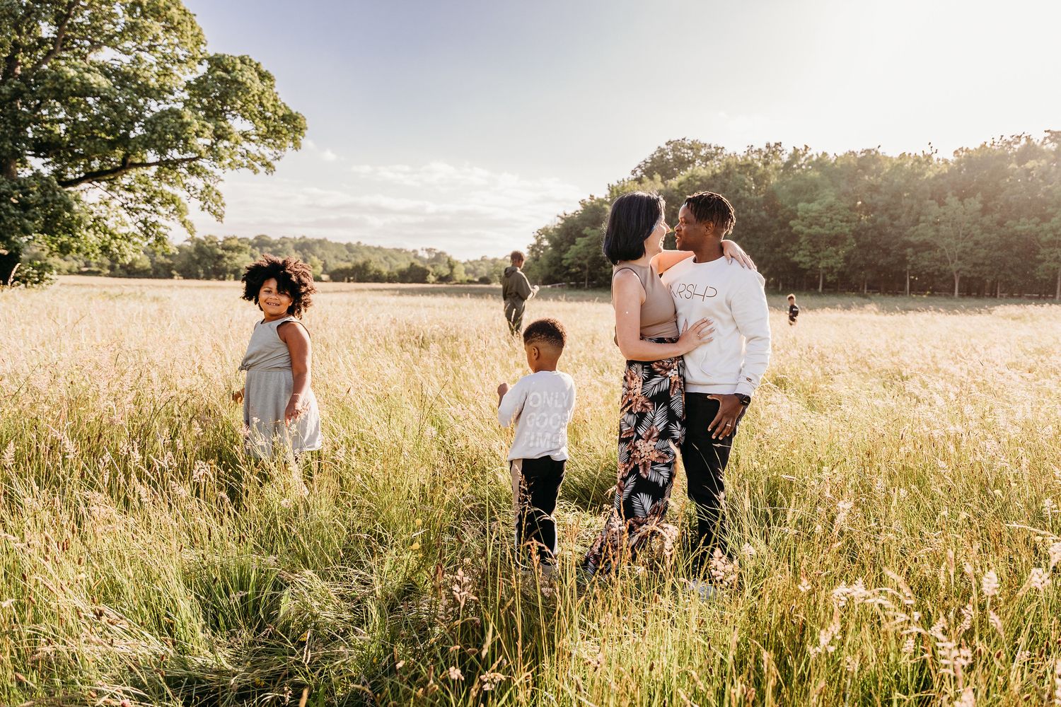 A group walks through a serene meadow with tall grass during sunset. family PHOTOGRAPHER Dublin