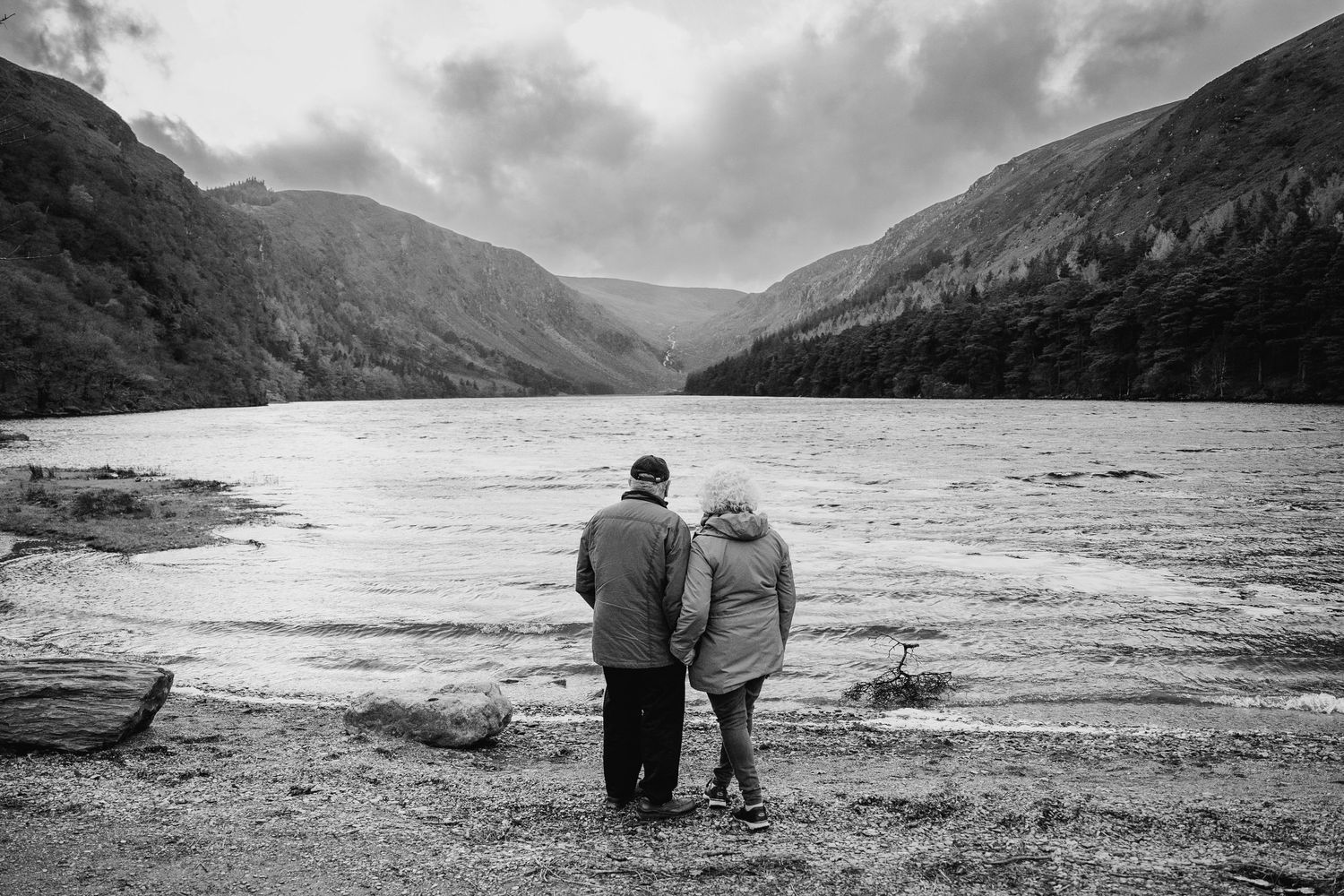 A black and white panoramic series of images showing two figures walking along a misty mountain lake shoreline. PHOTOGRAPHER Dublin ireland