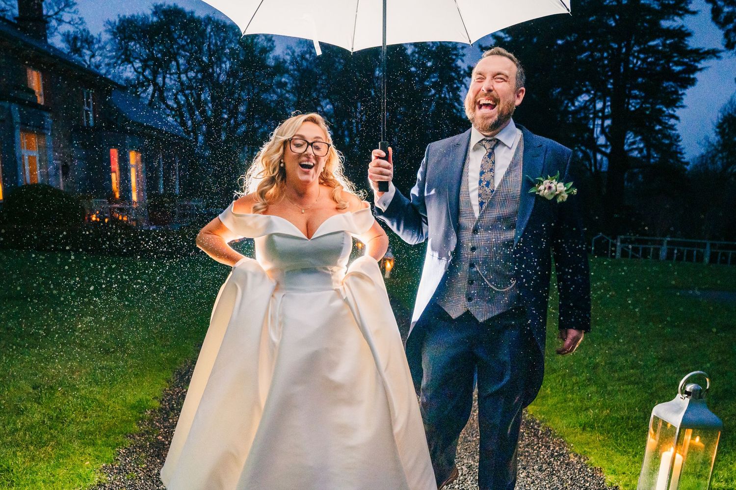Wedding celebration in the rain with umbrellas creating romantic ambiance at dusk.  Virginia Park Lodge Wedding Photographer Cavan Dublin Ir