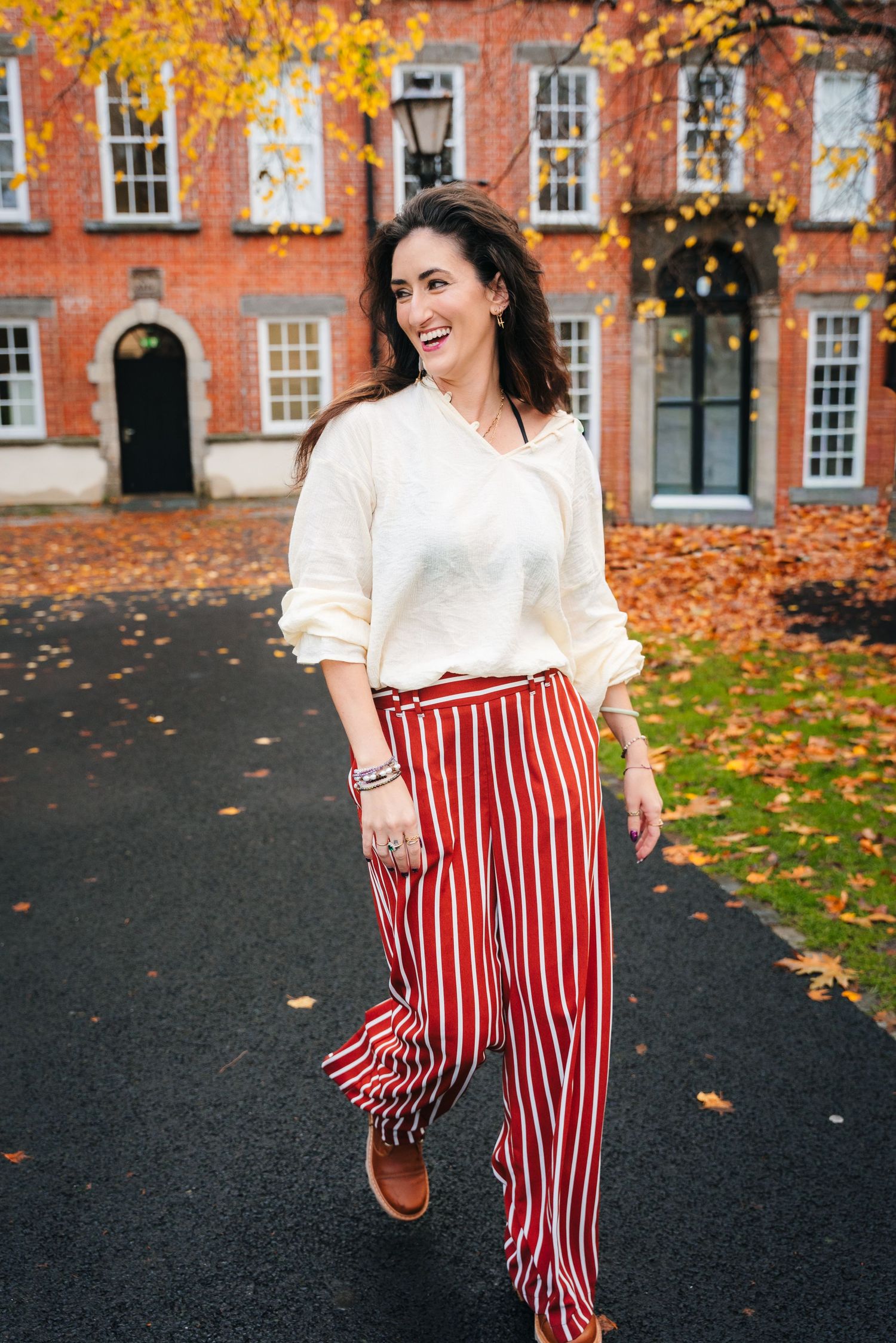 Autumn fashion shoot with red striped pants against brick building with fallen leaves. professional headshots dublin photographer