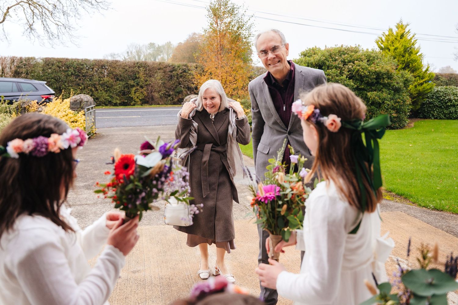 Wedding party celebrating outdoors in autumn with flower petals and joyful expressions.