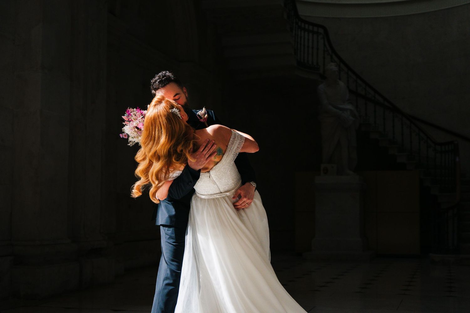A romantic wedding couple dancing in a dimly lit hallway with dramatic shadows and lighting.  city hall dublin wedding photos