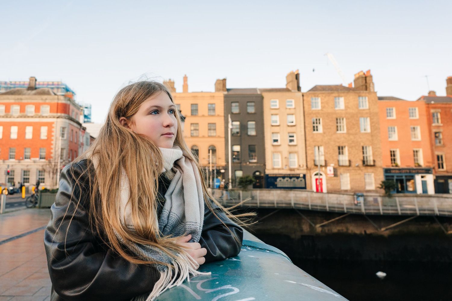 Person gazes at historic Georgian architecture along Dublin's waterfront during golden hour sunset.