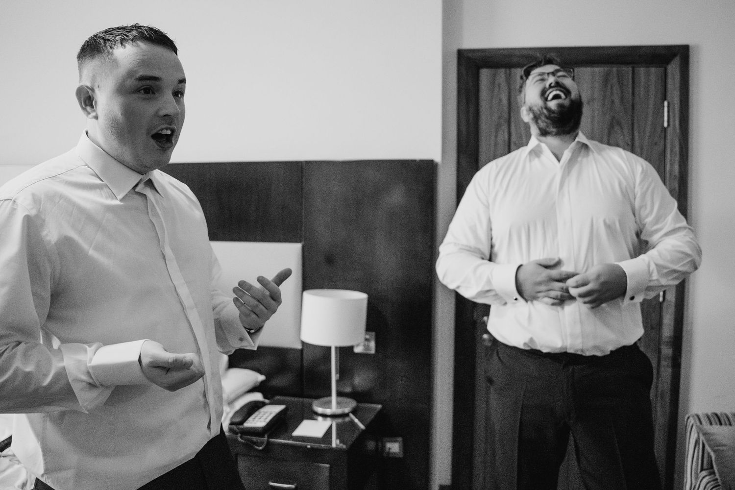 Two businessmen in white dress shirts share a candid moment in black and white photography. Wedding Photography Trim Castle Ireland