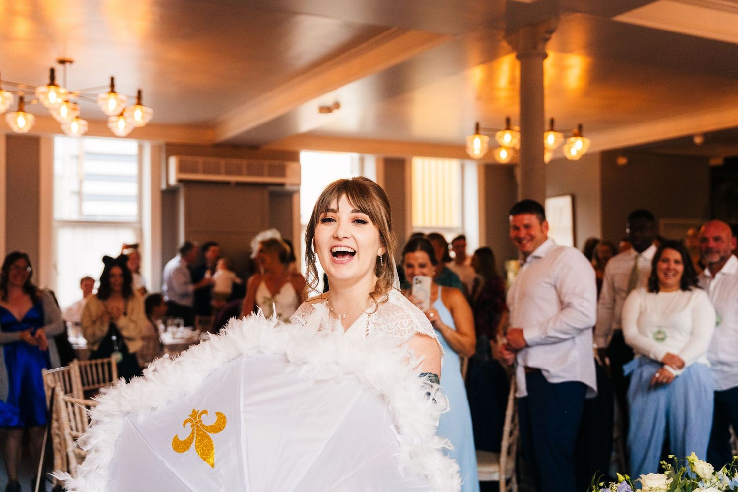 Wedding celebration features bride dancing with decorative parasol in elegant reception hall.PHOTOGRAPHER Dublin Ireland Wedding