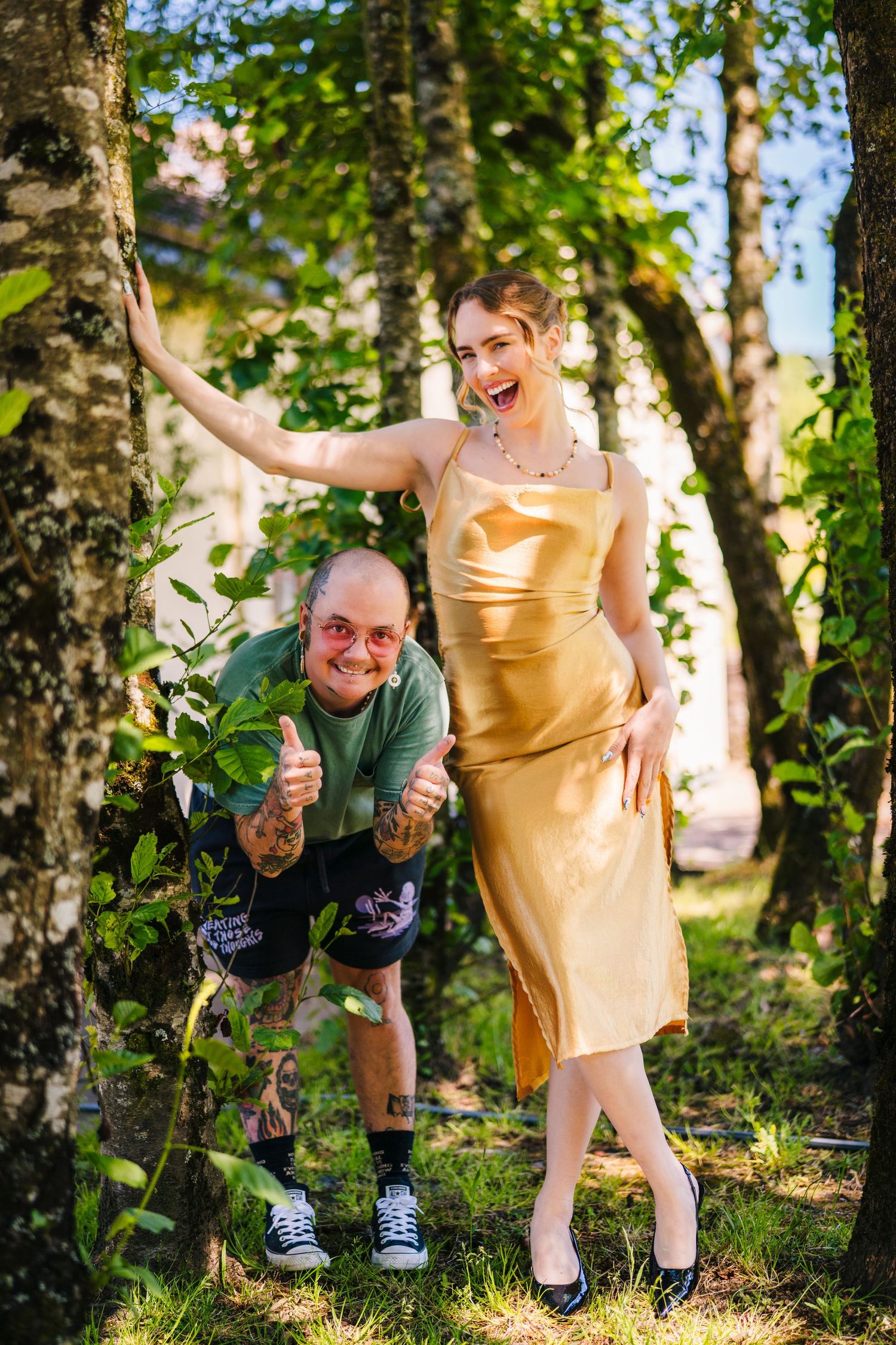Poulaphouca Wedding phoA playful candid moment between a couple in a wooded area, with gold dress and casual attire creating a fun contrast.
