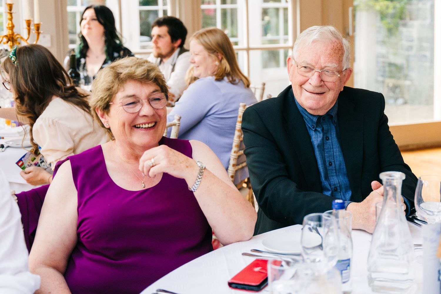 Millhouse slane wedding photographer dublin Wedding guests enjoying themselves at a reception table indoors.