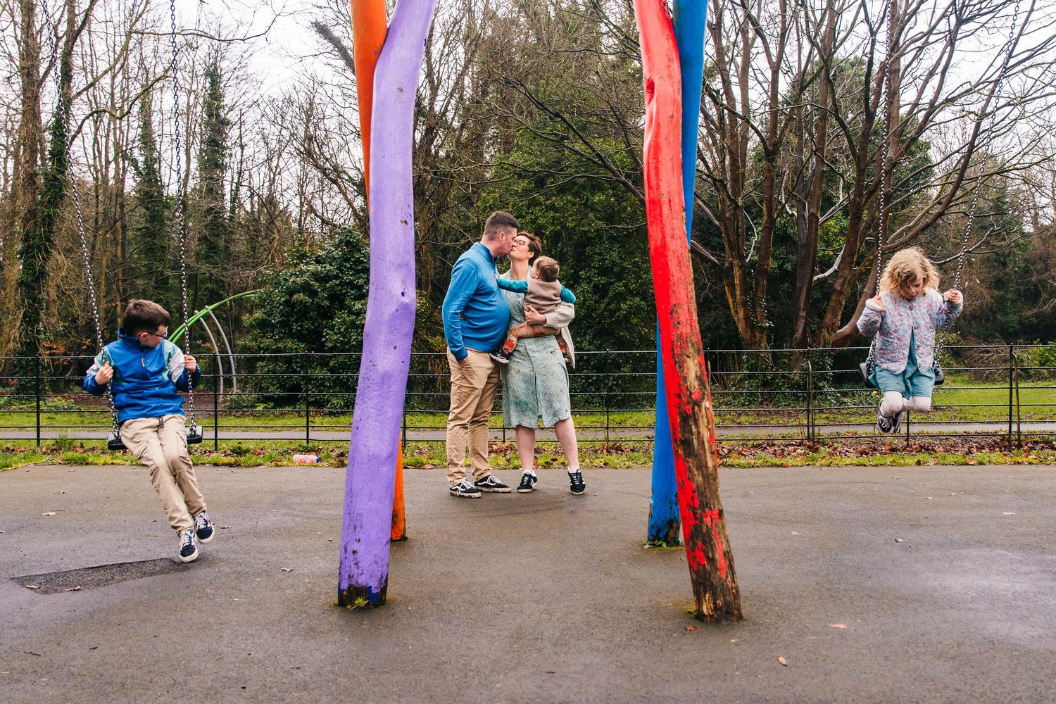 Family photographer Dublin Ireland  Children playing around colorful outdoor posts in a playground setting.