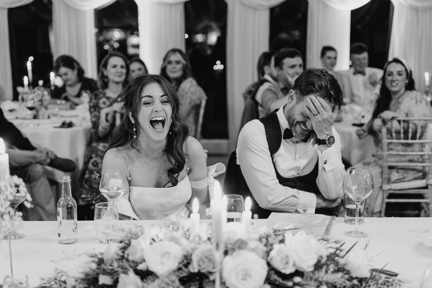 Castle Leslie Wedding Photographer Dublin Wedding reception guests react with laughter during dinner speeches under elegant white draping.
