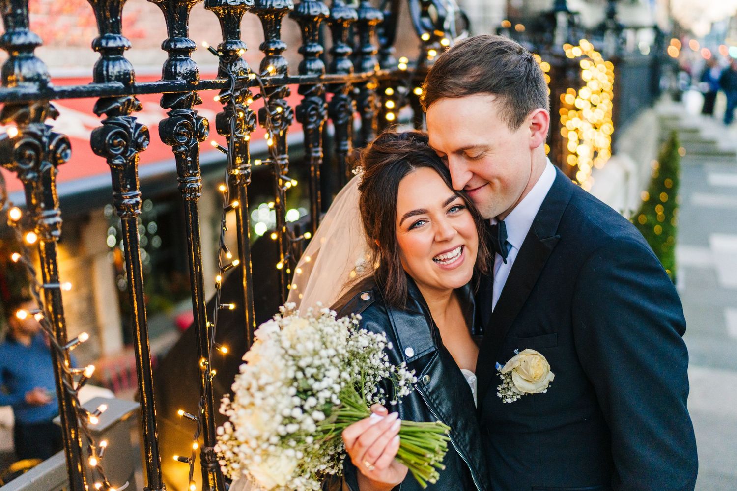 Candid wedding portrait with fairy lights and iron railings creating romantic ambiance. Wedding PHOTOGRAPHER Dublin