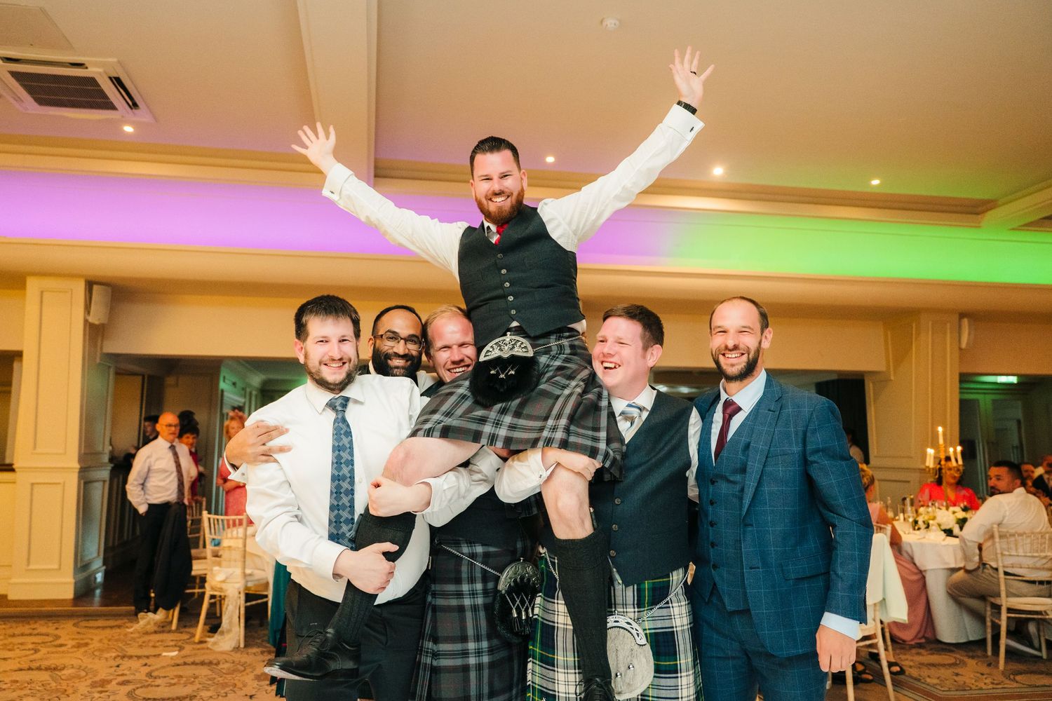 Wedding reception venue with colorful LED mood lighting and guests celebrating. Portmarnock Hotel Wedding PHOTOGRAPHER Dublin