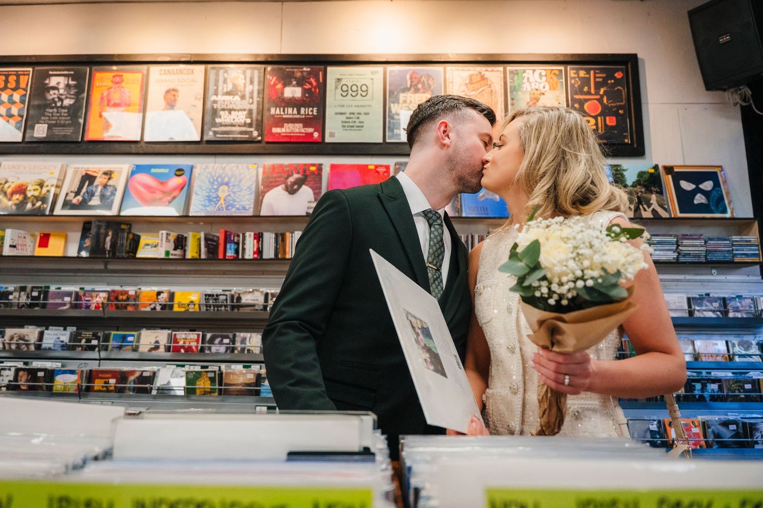 Couple sharing intimate moment in record store surrounded by album covers and displays. City Hall Dublin wedding photogrAPher