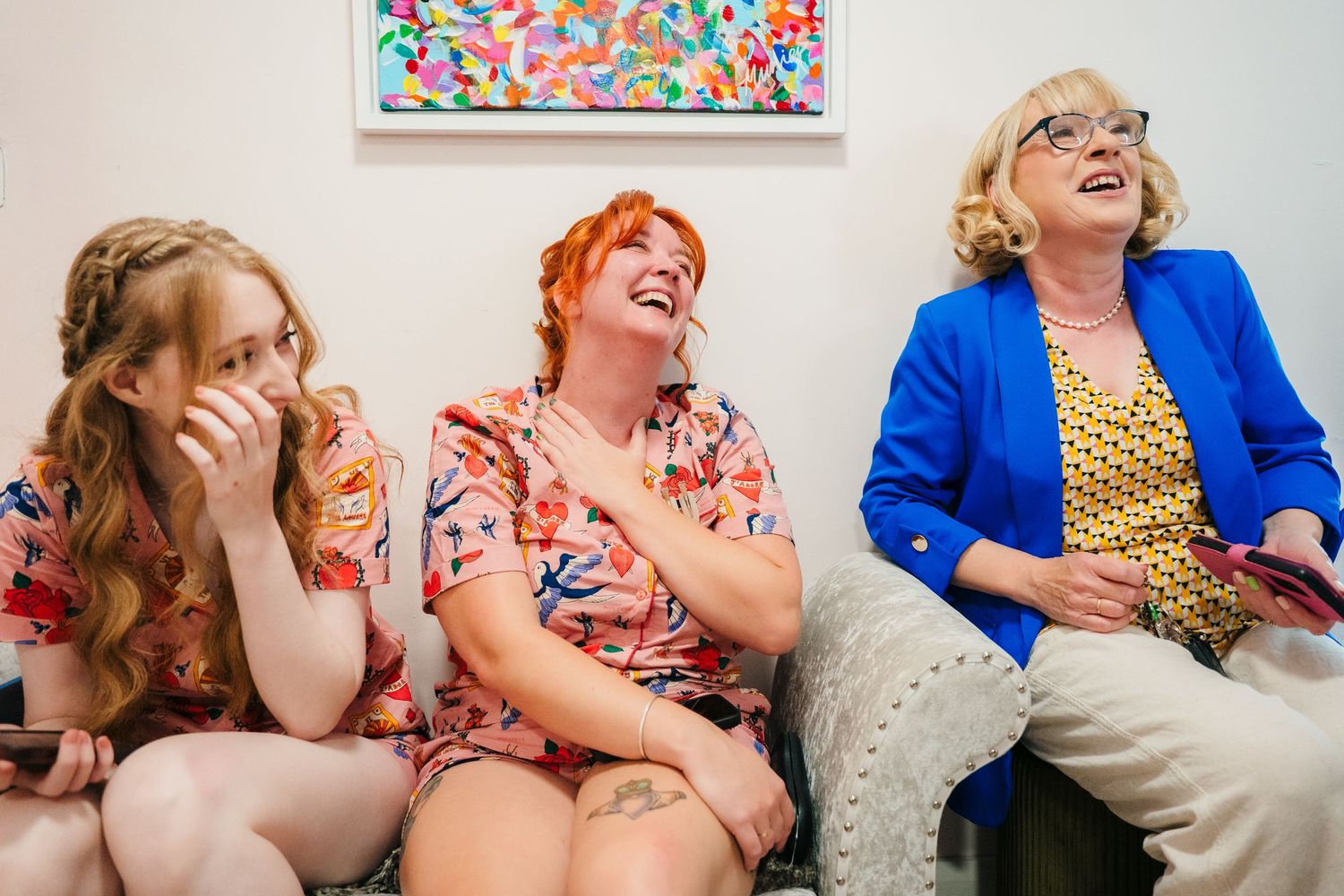 A lively wedding party laughing and having fun together, with bright blue and floral dresses . Village Barn Tyrrellspass wedding photographe