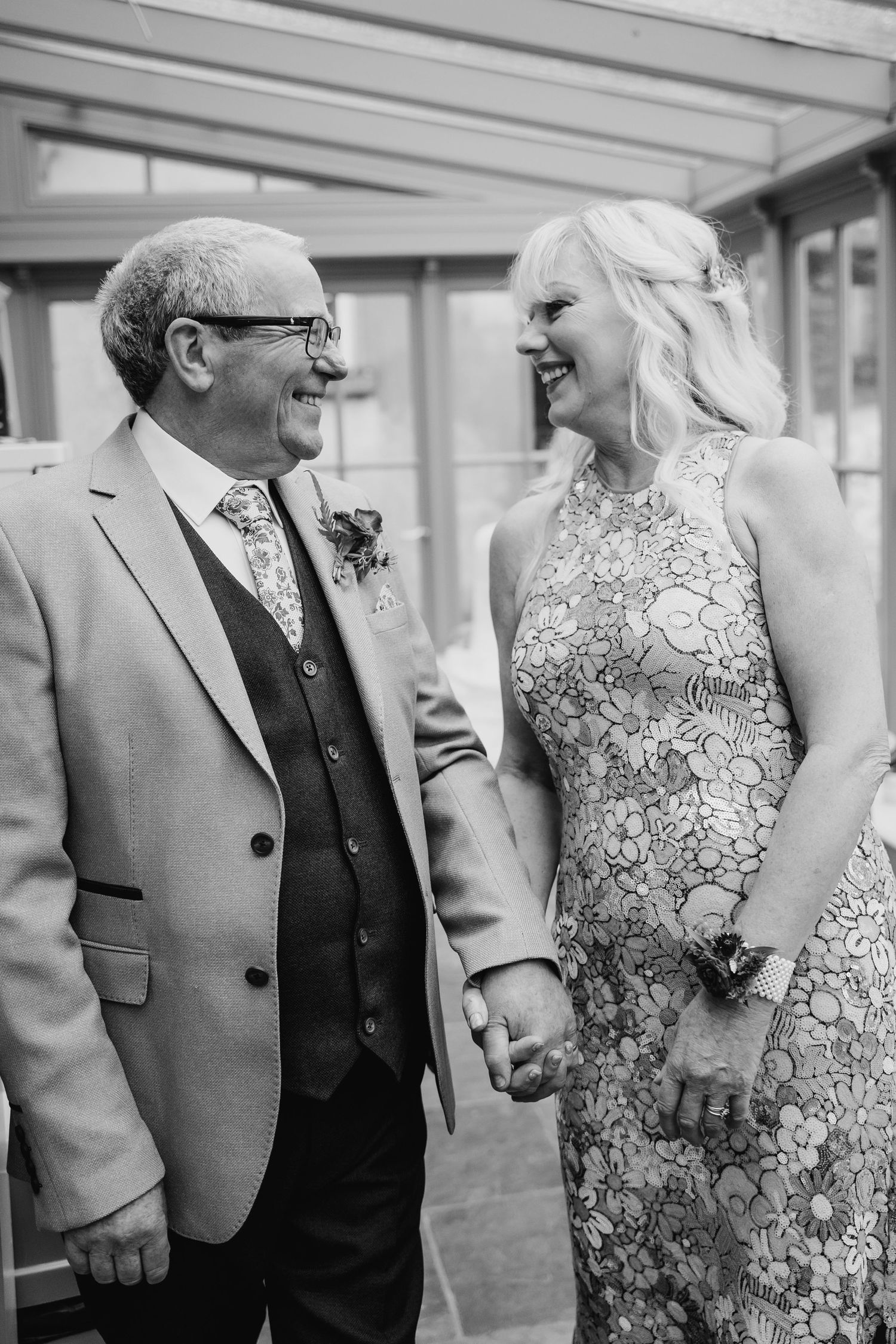 Black and white photo showing wedding guests in formal attire sharing a light-hearted moment. Wedding photographer Dublin