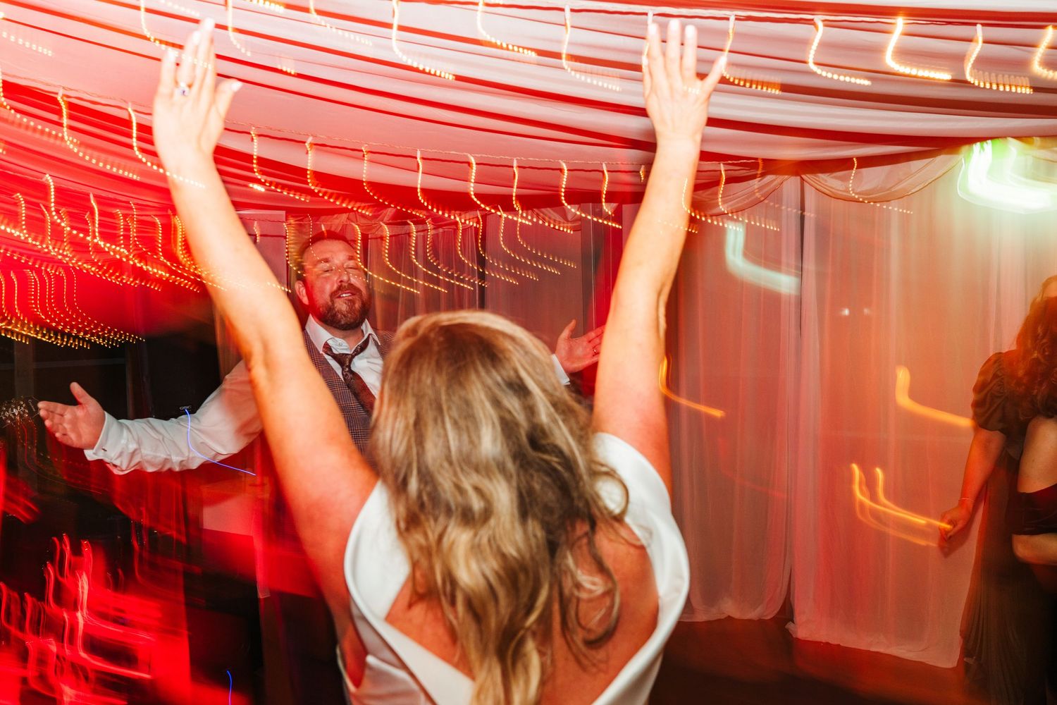 Dance floor glowing with vibrant red lighting during lively wedding celebration.  Virginia Park Lodge Wedding Photographer Cavan Dublin Irel