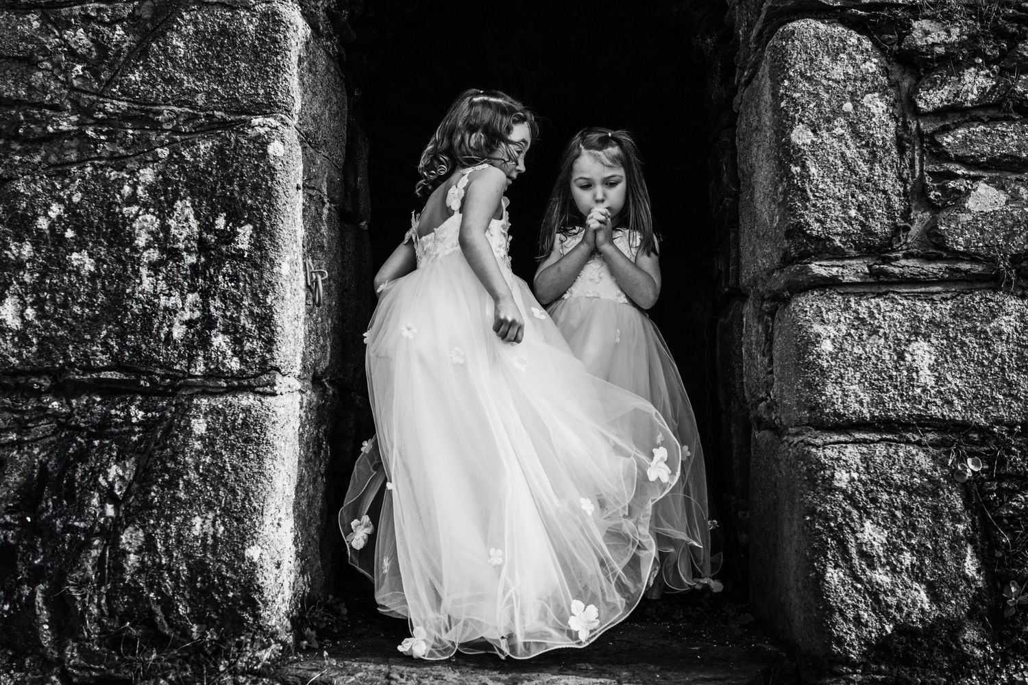 Wedding couple embraces near textured stone wall in dramatic black and white composition. Wedding PHOTOGRAPHER Dublin