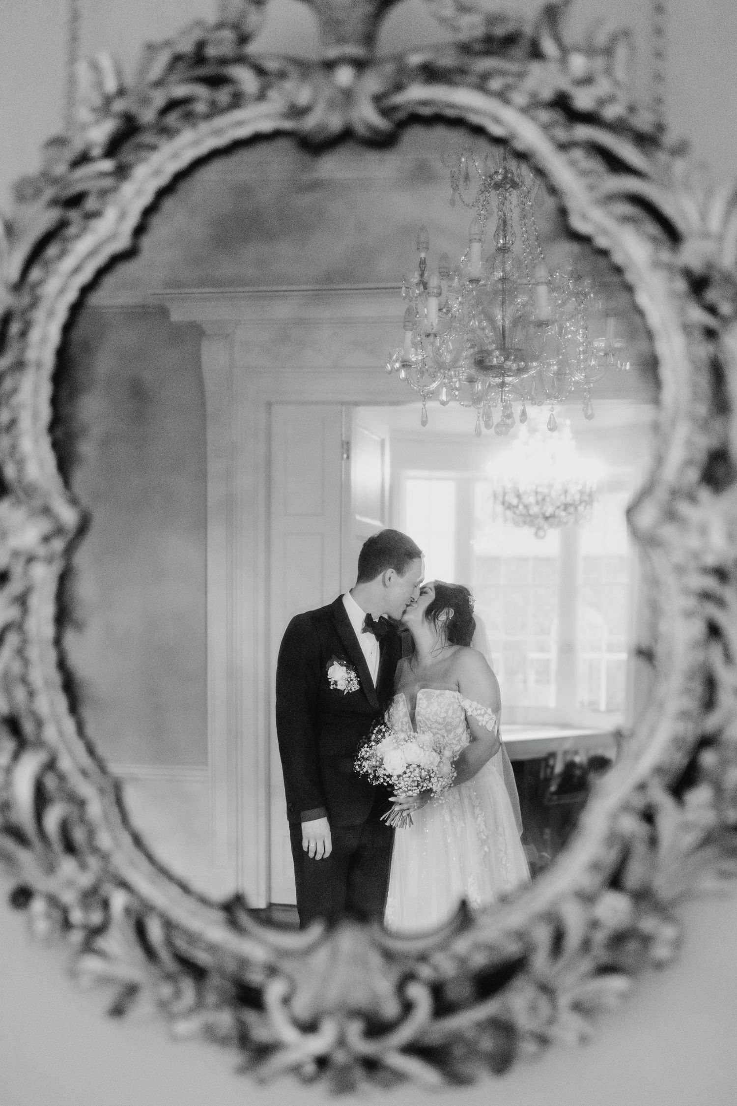 A romantic wedding scene reflected in an ornate vintage mirror with crystal chandeliers in background. Wedding PHOTOGRAPHER Dublin