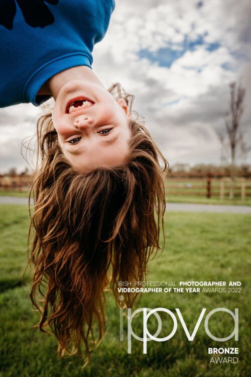 Long brown hair flows freely as someone hangs upside down against a cloudy sky in a playful moment. PHOTOGRAPHER Dublin