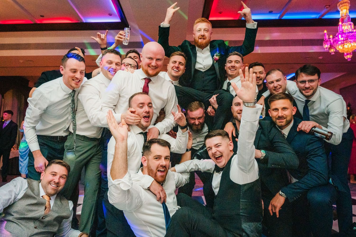 Wedding party guests celebrating and posing together under colorful party lighting. Wedding photographer dublin