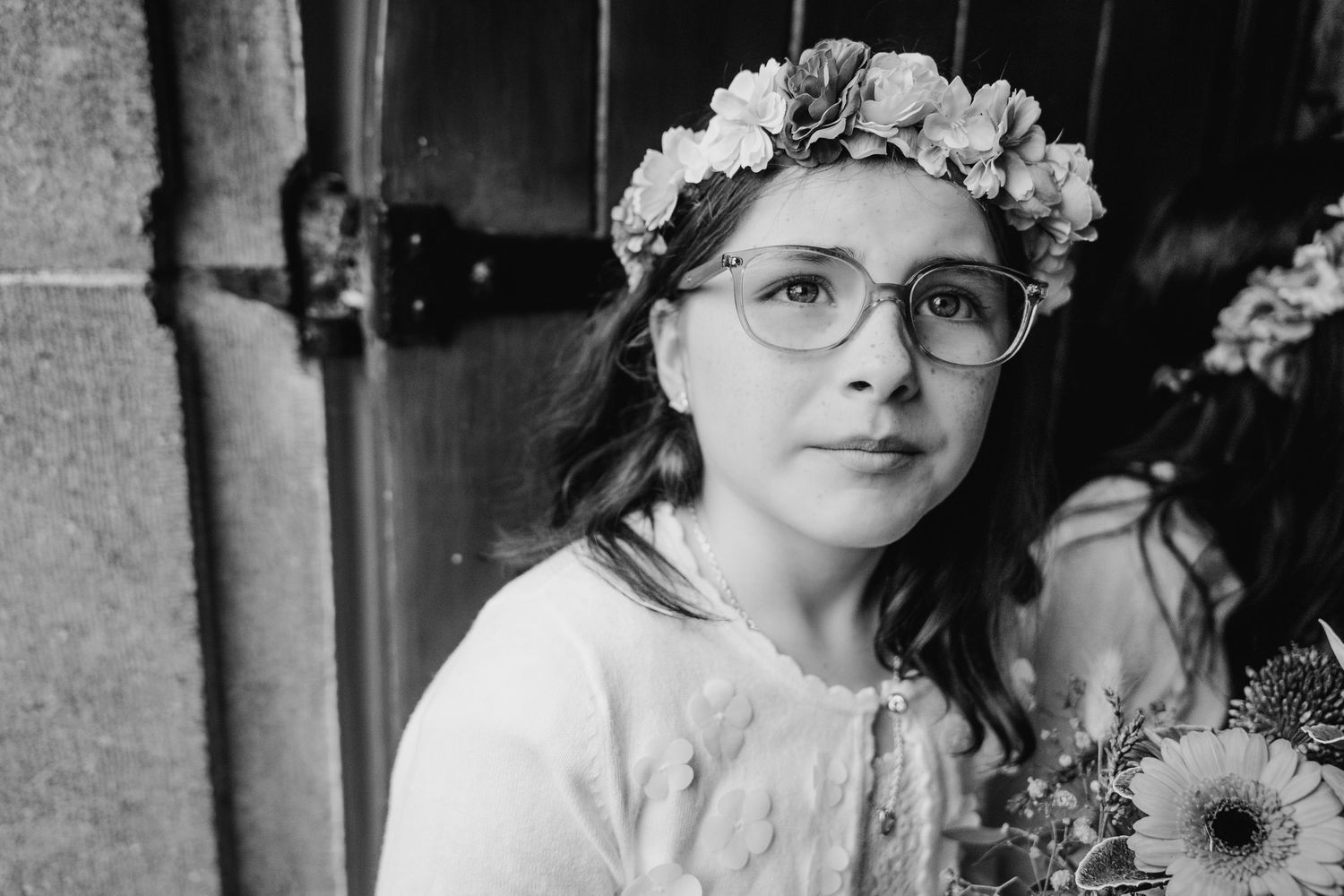 Black and white portraits of wedding party members wearing floral crowns and glasses.