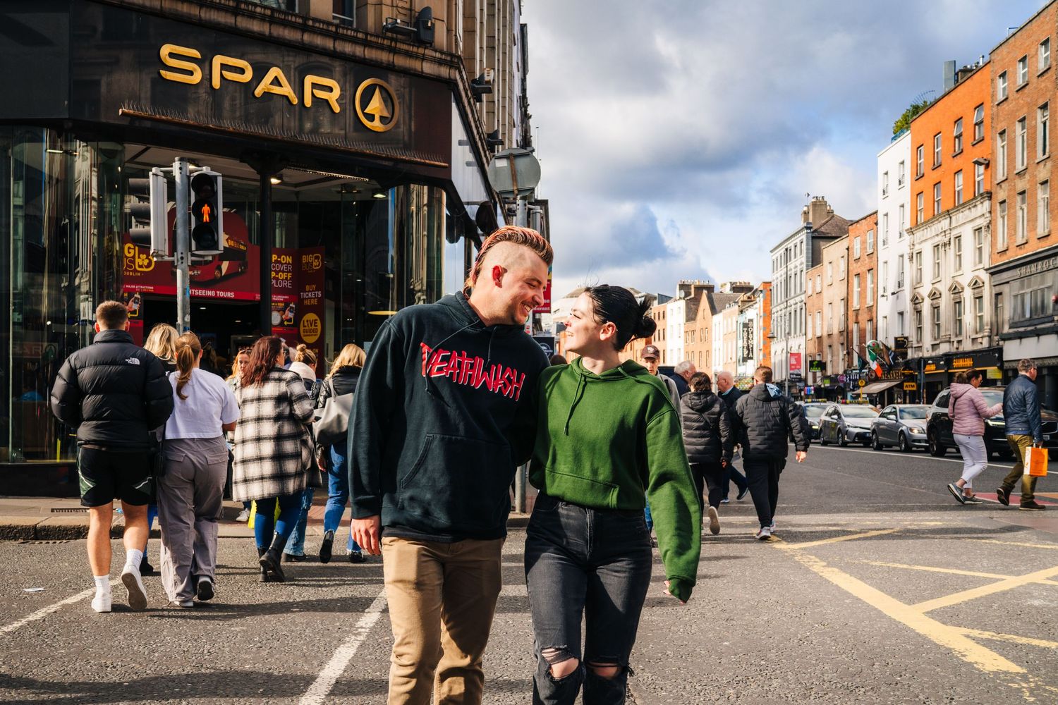 A couple walking down a Dublin street past the SPAR store on a cloudy day. PHOTOGRAPHER Dublin Ireland