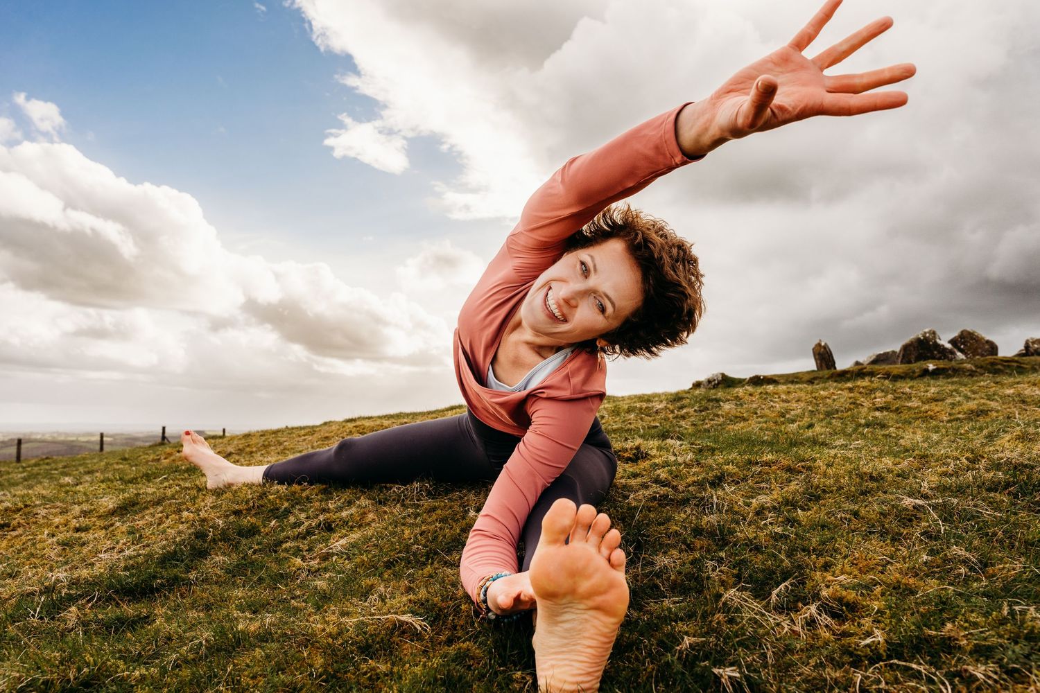 Person in coral dress dances gracefully across a windswept hilltop landscape at sunset. Portrait PHOTOGRAPHER Dublin