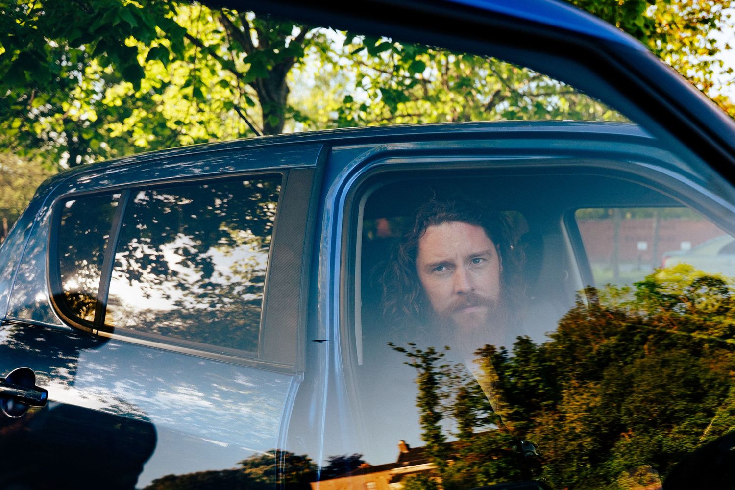View through a car window showing trees and greenery reflected in the glass. PHOTOGRAPHER Dublin