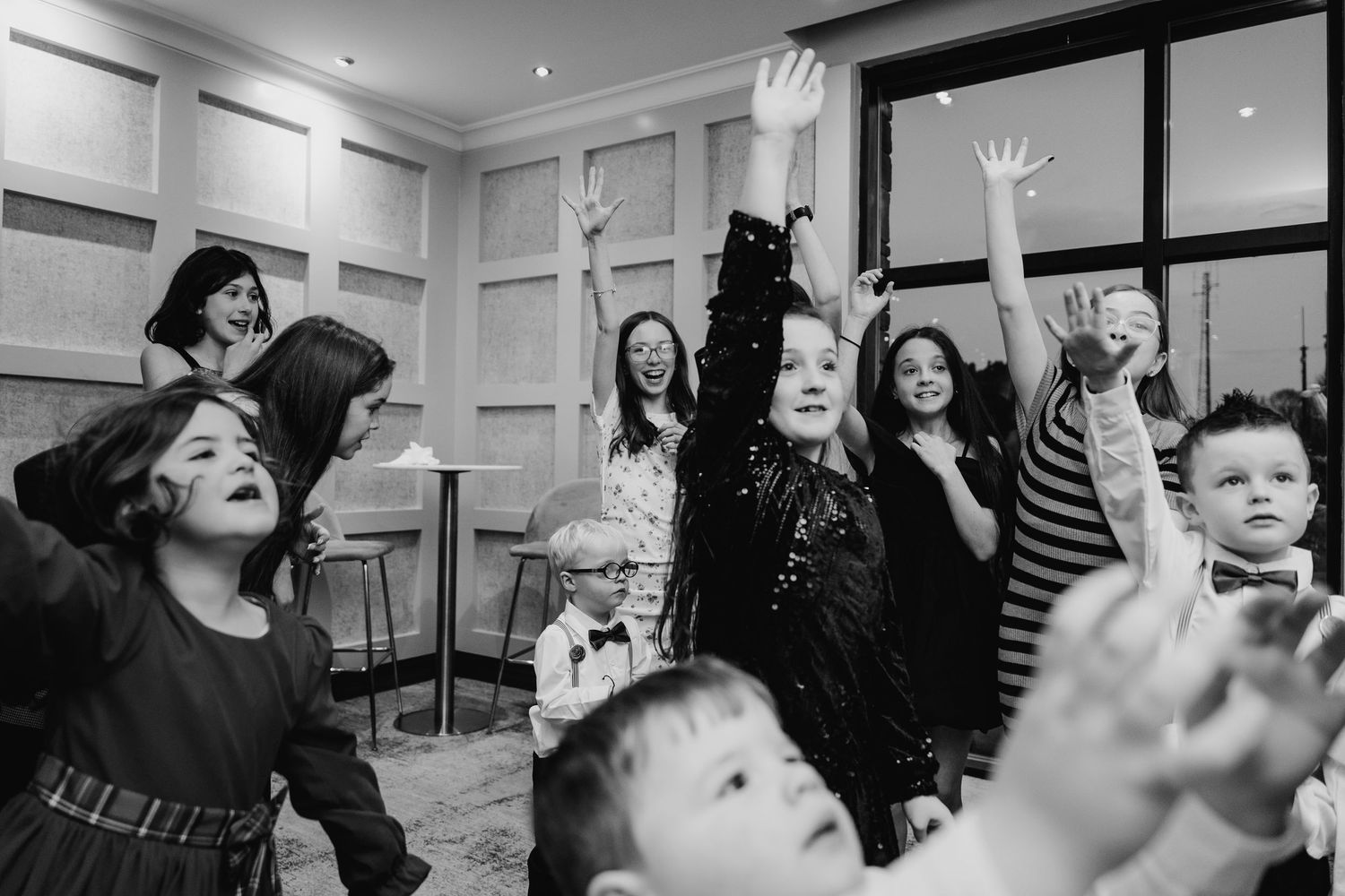 Wedding party performs choreographed dance moves in a bright indoor venue.  Wedding PHOTOGRAPHER Trim Castle