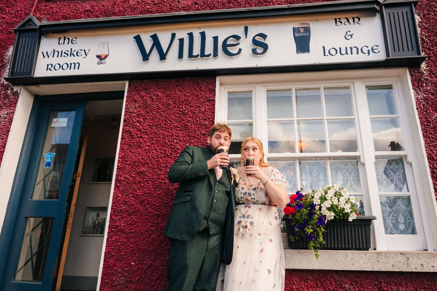 Outdoor view of Willie's Lounge with red exterior wall and white signage. . Village Barn Tyrrellspass wedding photographer Ireland