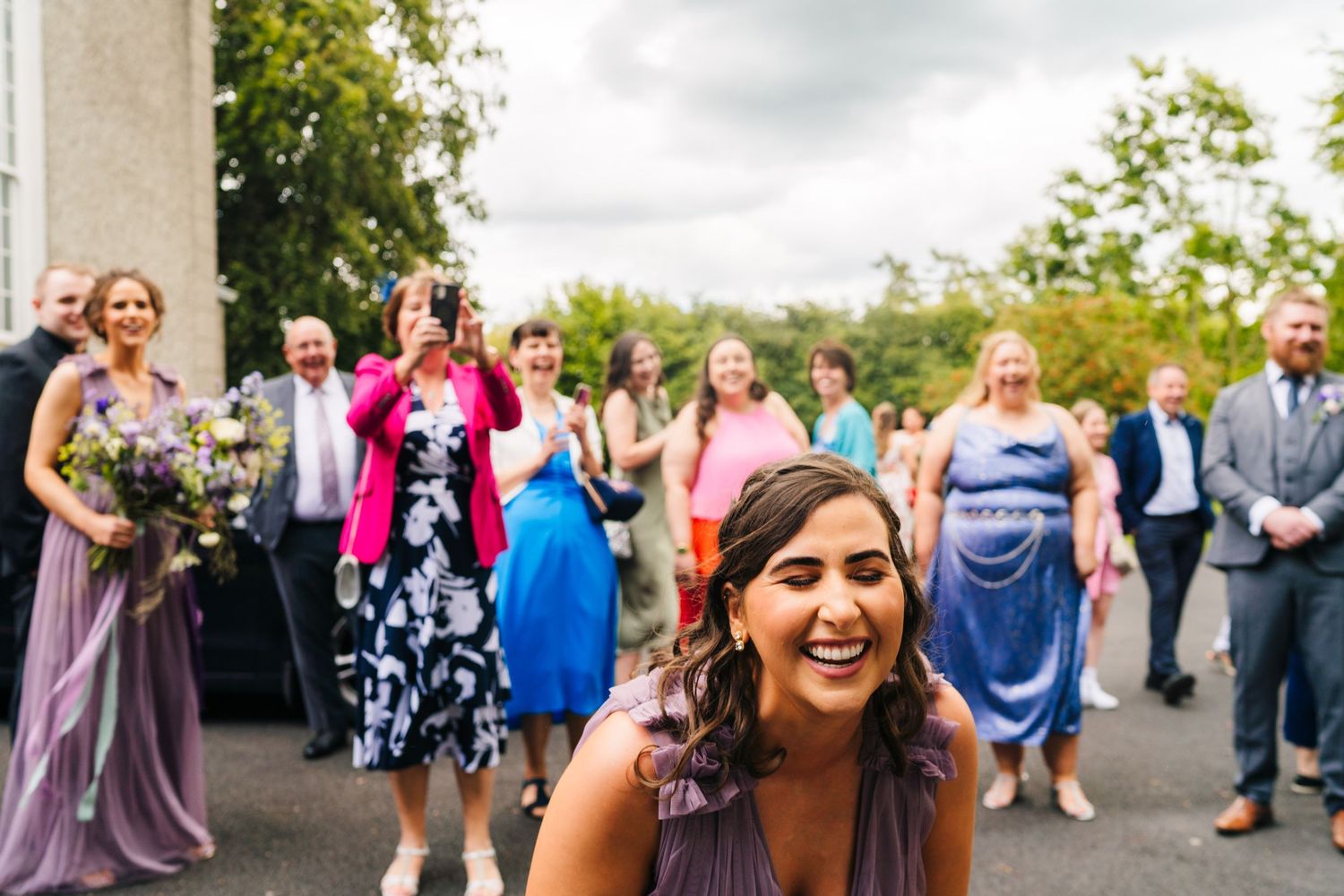 Millhouse slane wedding photographer dublin Panoramic view of wedding guests gathering outside a church after the ceremony.