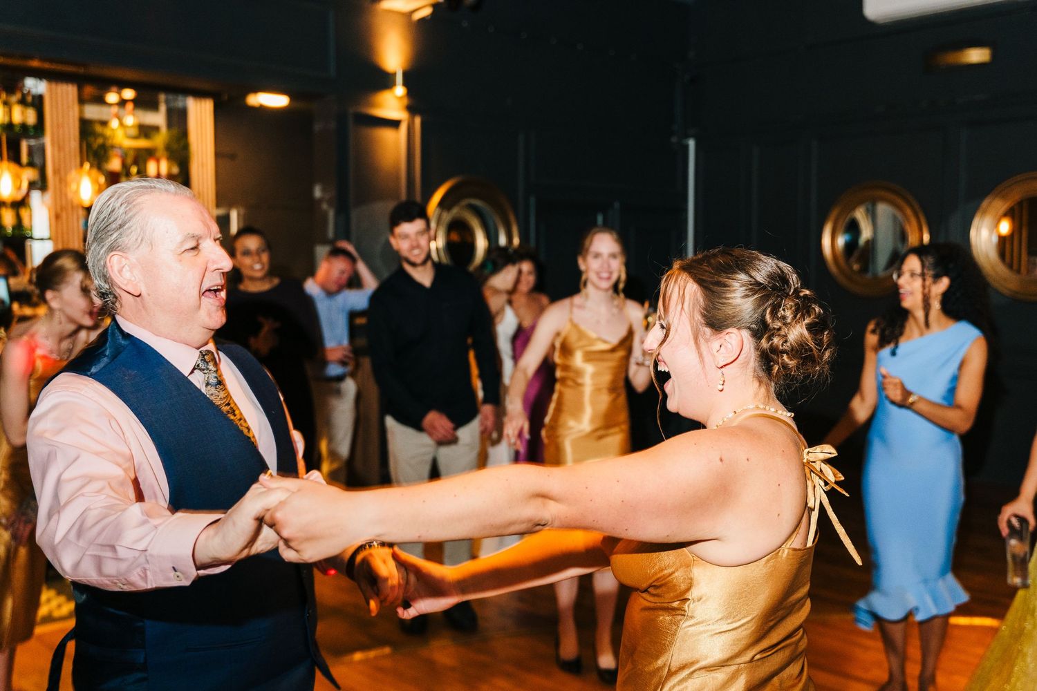 Poulaphouca Wedding photographer wicklow  Wedding guests dancing joyfully on a wooden dance floor during an indoor reception celebration.