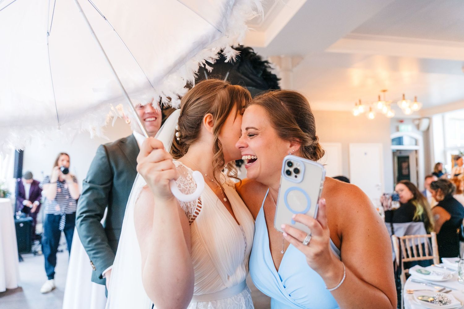 Two wedding guests share a joyful moment under a white tent during reception celebrations. PHOTOGRAPHER Dublin Ireland Wedding