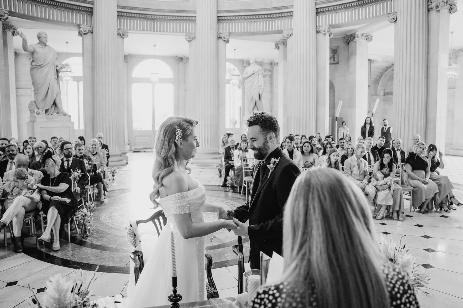 Grand interior of historic building with columns and gathered wedding guests.  city hall dublin wedding photos