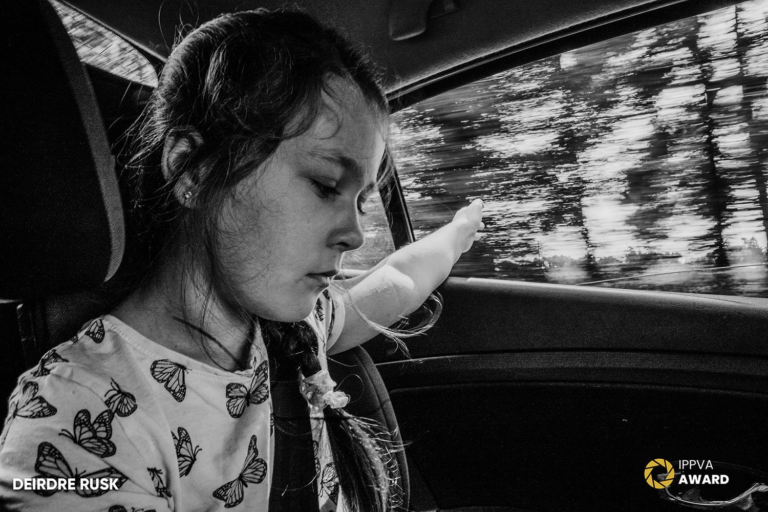 Black and white photograph of a car passenger resting against the window with motion blur outside. PHOTOGRAPHER Dublin