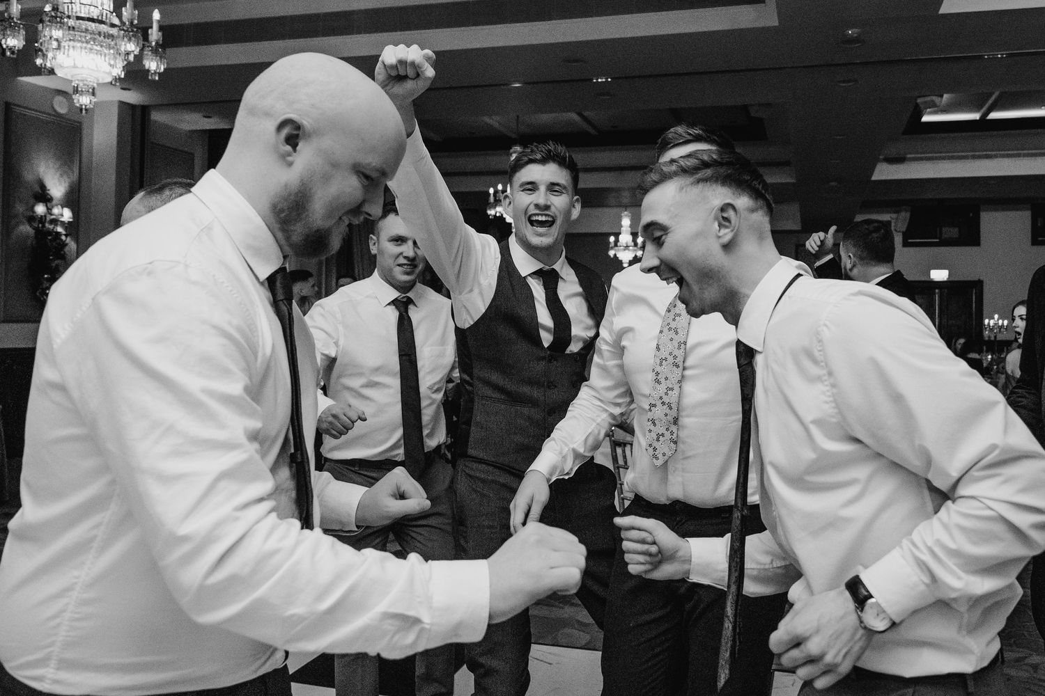 Wedding guests in formal attire dancing and celebrating during lively reception party. Wedding photographer dublin