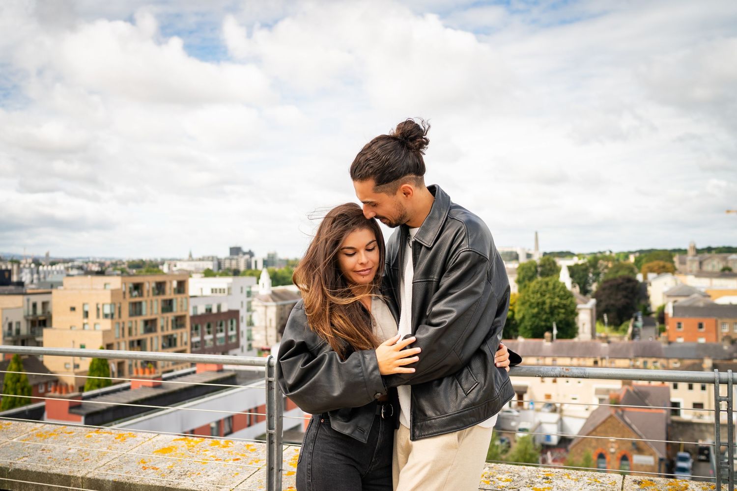 A couple enjoying scenic views from a rooftop terrace in an urban setting with cloudy skies in the background. Couple's Photoshoot PHOTOGRAP