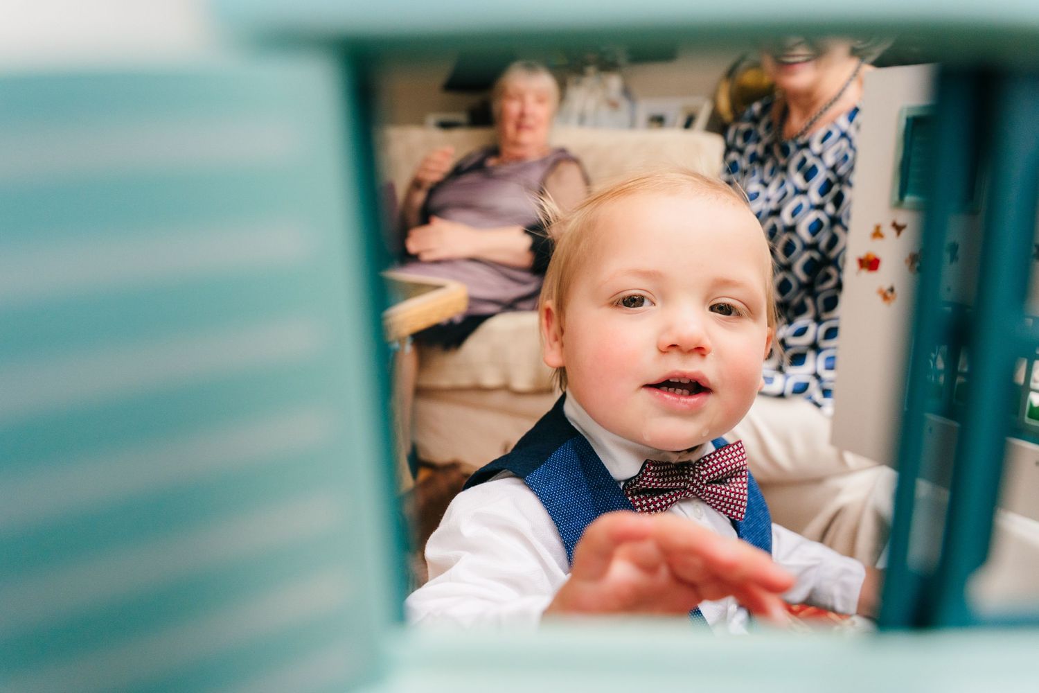 Small child wearing a bow tie and white shirt smiles while sitting at a dining table. family PHOTOGRAPHER Dublin