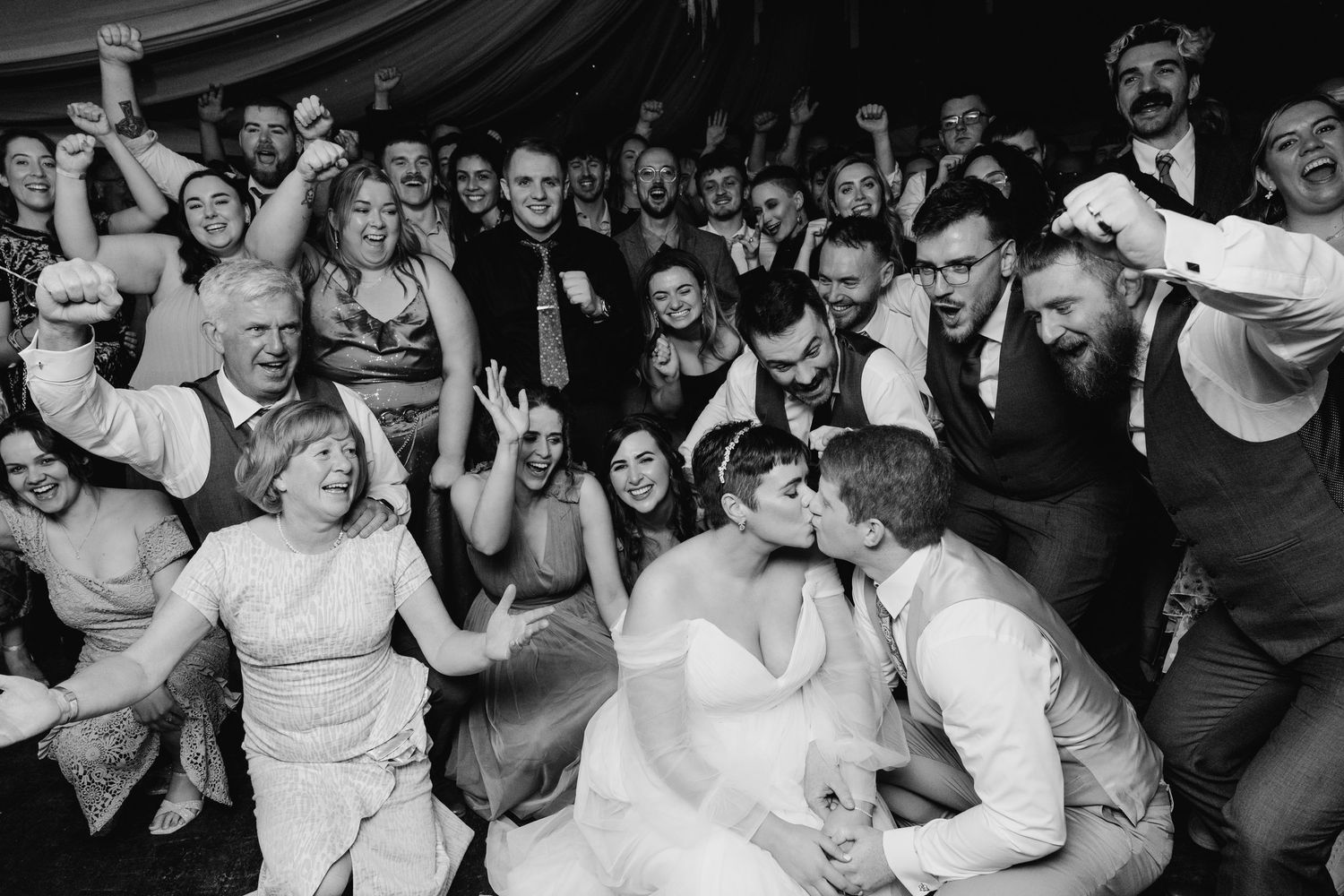Black and white photo of an energetic wedding reception dance floor with guests celebrating and dancing Dublin. Wedding PHOTOGRAPHER Dubli