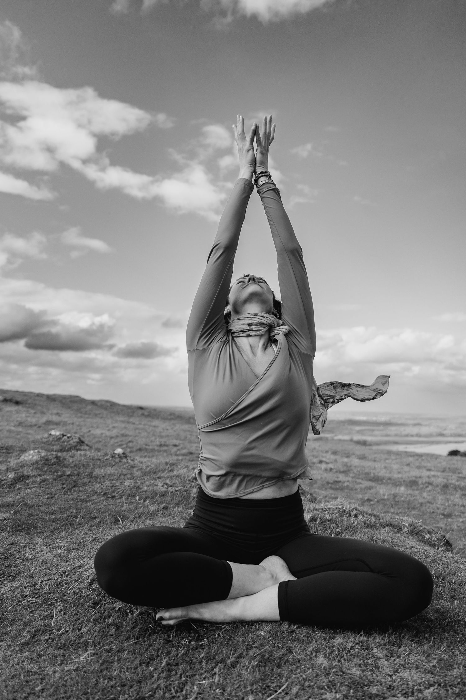 A progressive sequence of yoga poses on a grassy hilltop shows stretching movements in black and white photography. Portrait PHOTOGRAPHER Du