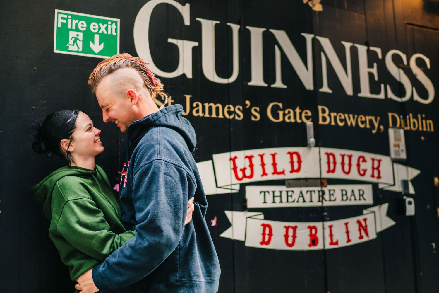 A couple embraces in front of the Guinness St. James's Gate Brewery sign in Dublin. PHOTOGRAPHER Dublin Ireland