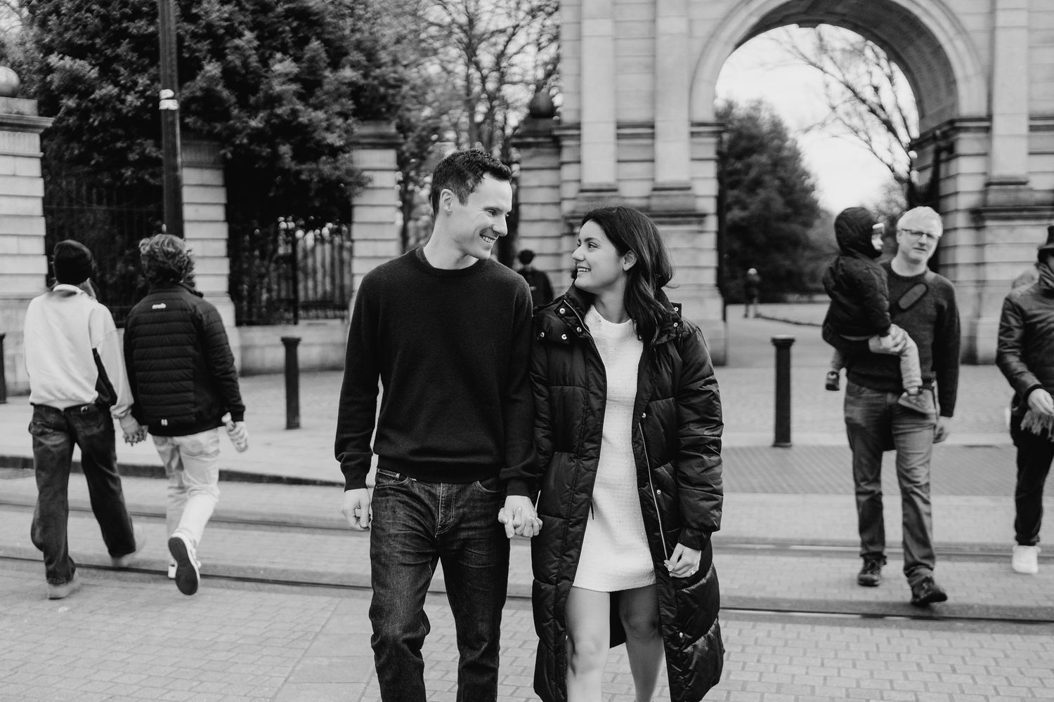 A couple walking together on a cobblestone street near historic architecture. Surprise proposal dublin photography