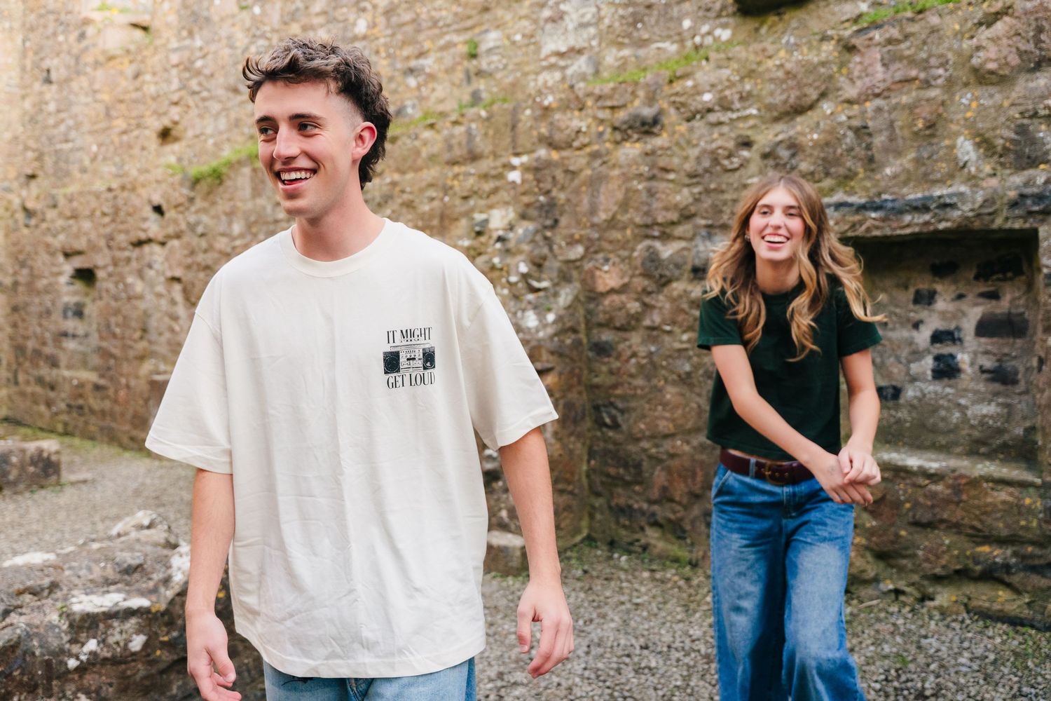 Two people standing by a stone wall wearing casual clothing on a sunny day. Photographer Ireland dublin