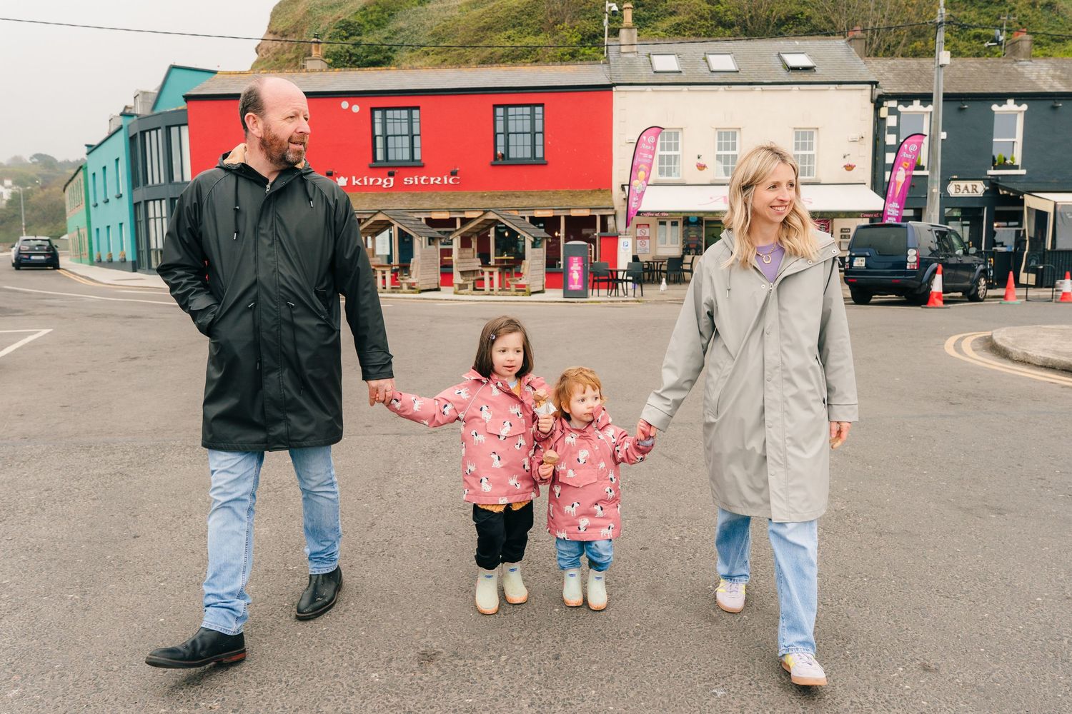 Family walking together on a sidewalk outside colorful storefronts in small town setting. PHOTOGRAPHER Dublin