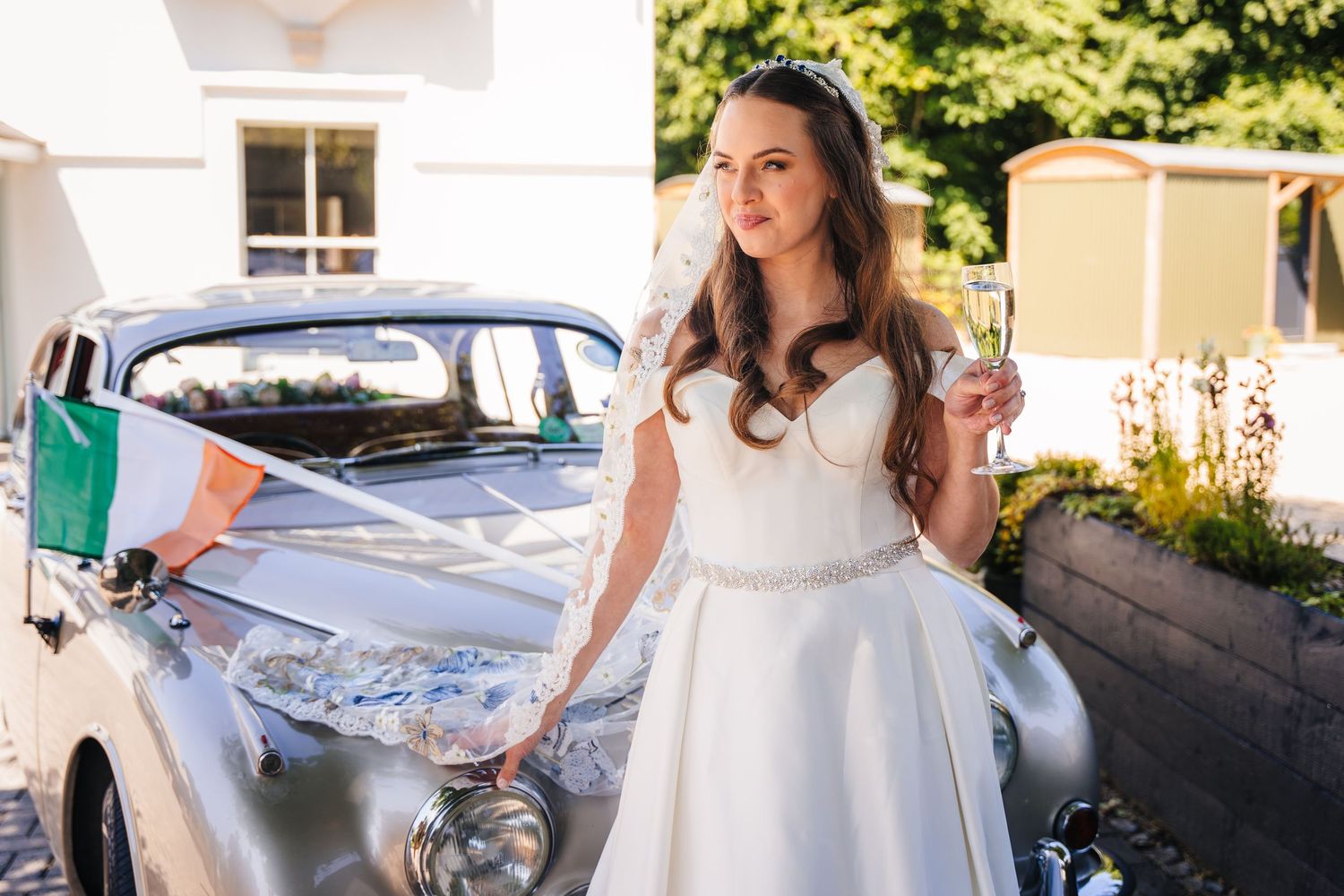 Poulaphouca Wedding photographer wicklow  A classic vintage car stands elegantly beside someone wearing a white wedding dress.